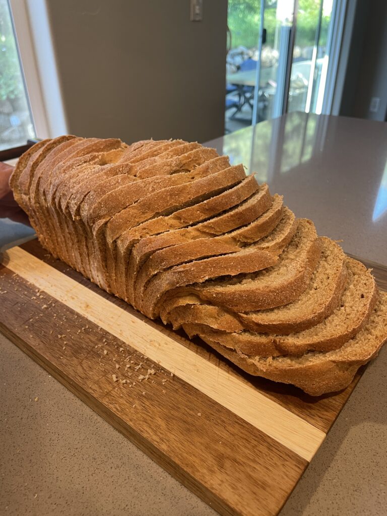 Soft and fluffy sandwich bread made with fresh milled flour, sliced on a wood board