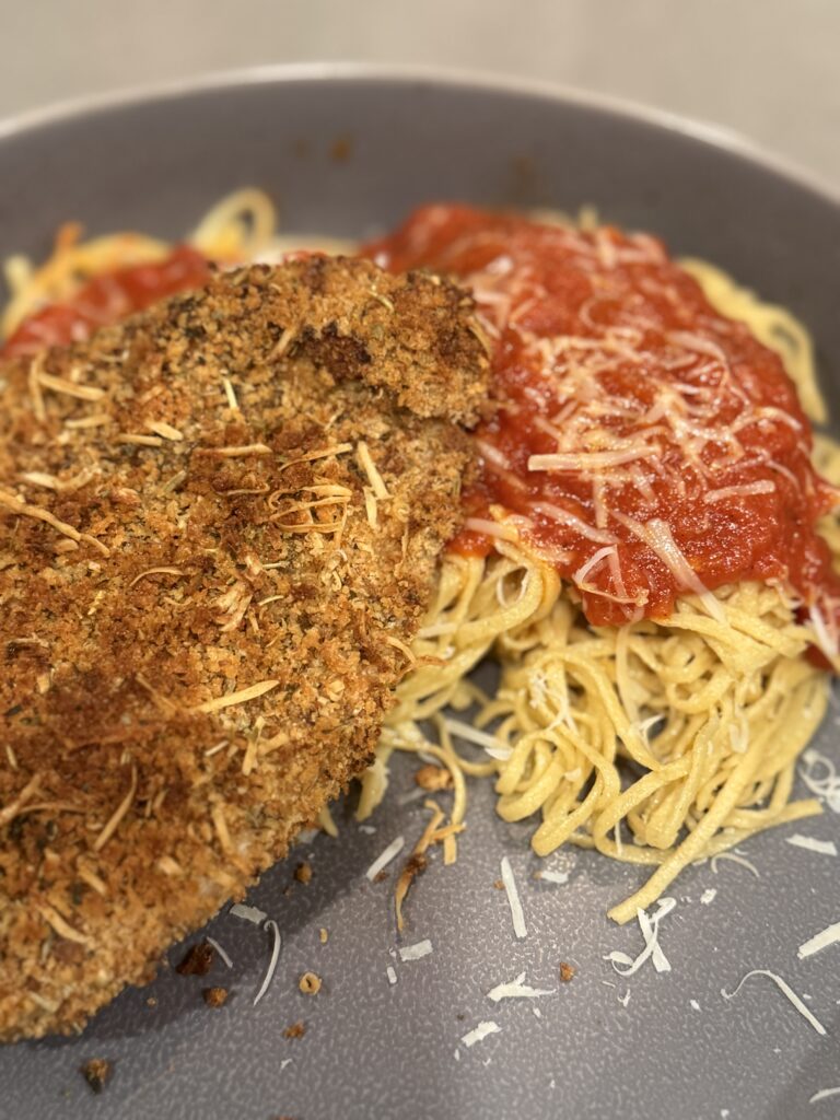 Fresh milled flour chicken Parmesan served over homemade fresh milled pasta with marinara sauce and parmesan cheese.
