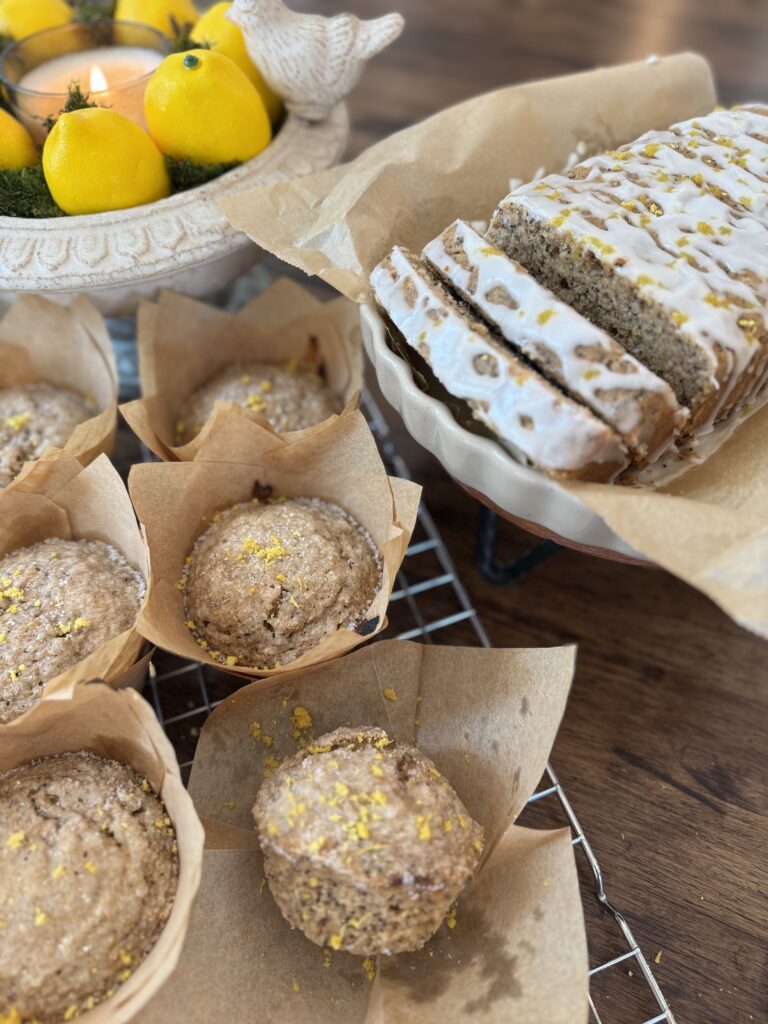 Lemon poppyseed muffins made with fresh milled flour cooling on a rack next to a lemon poppyseed loaf drizzled with lemon glaze.